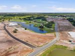 Aerial view of a construction site and a new golf course with a winding road, green fairways, and water features.