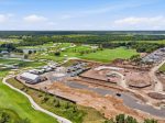 Aerial view of a golf course under construction with green fairways, water hazards, and a construction site on the right.